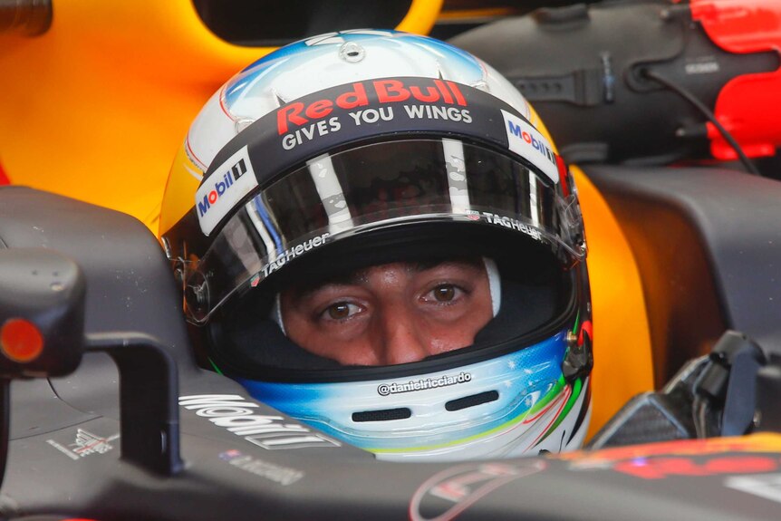 Daniel Ricciardo sits in his car with his helmet on during a pit stop.