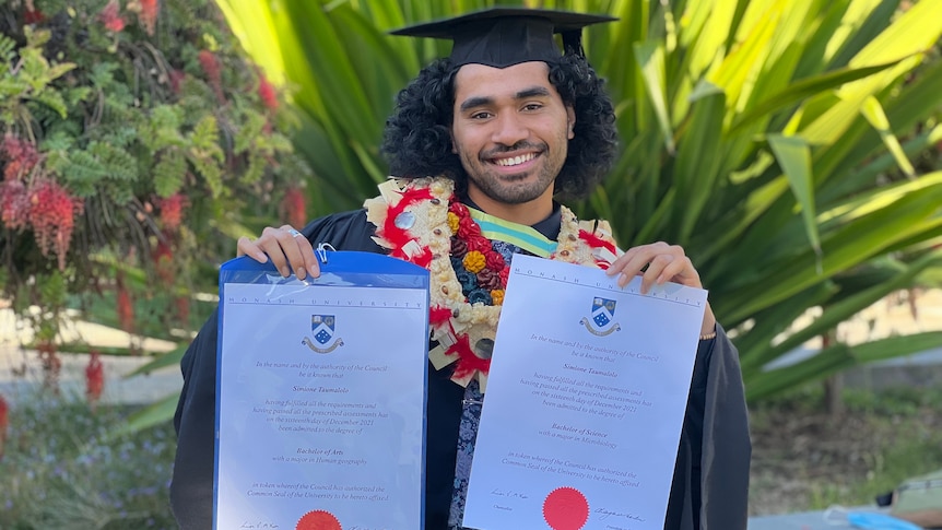 Simione Taumalolo holding up his graduation certificates.