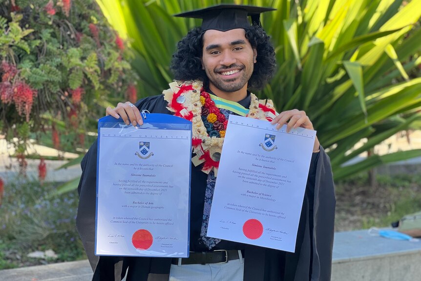 Simione Taumalolo holding up his graduation certificates.