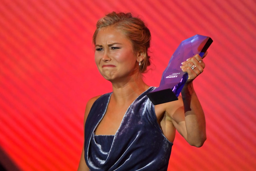 Grace cries while holding her award up.