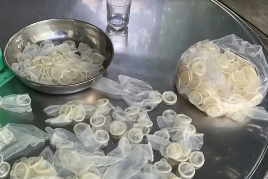 Condoms splayed on a table and in a bowl.