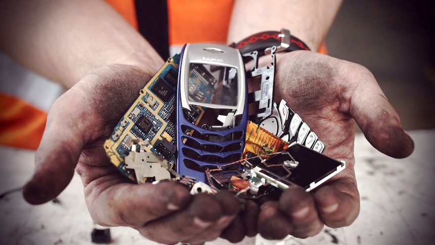 Two hands hold the broken down components of a mobile phone.