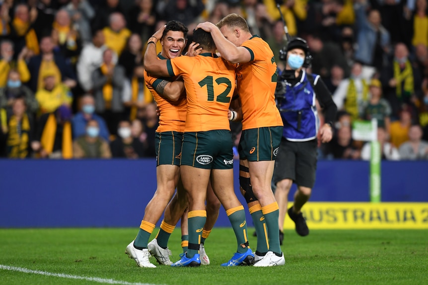 Three Wallabies players celebrate a try against France.
