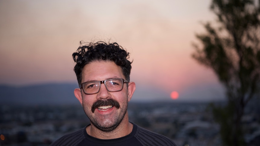 Layne Brown smiles at the camera with a setting sun behind him.