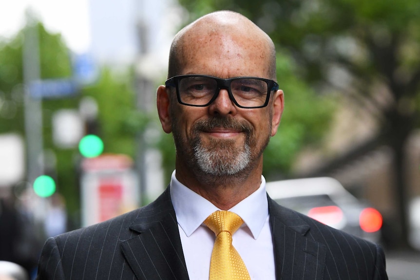 Simon Overland wears a suit and yellow tie.