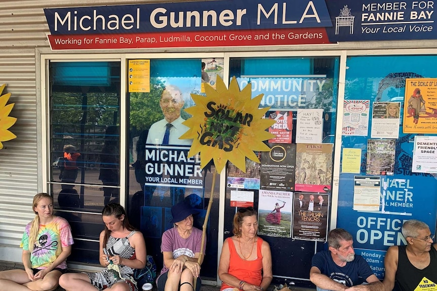 6 protesters sit down outside Michael Gunner's office.
