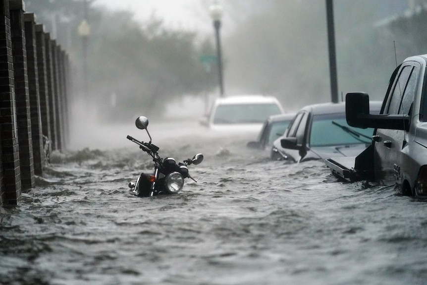 A motorbike and cars submerged in water.