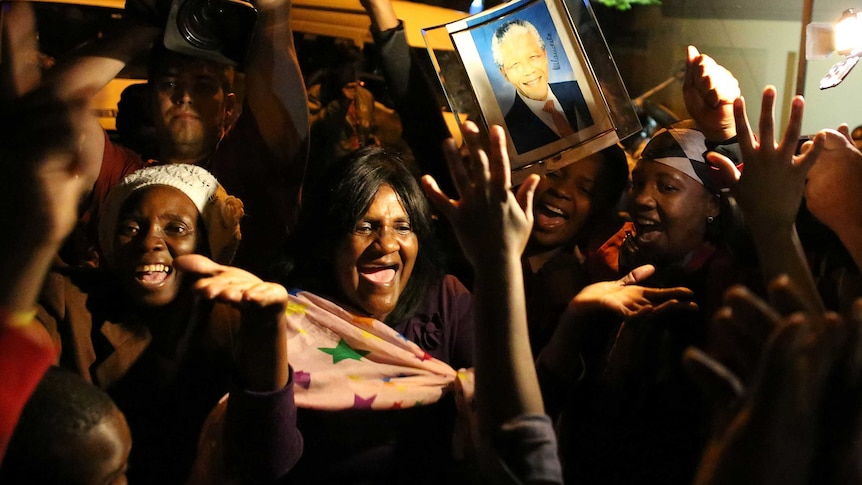 South Africans hold pictures of former South African president Nelson Mandela