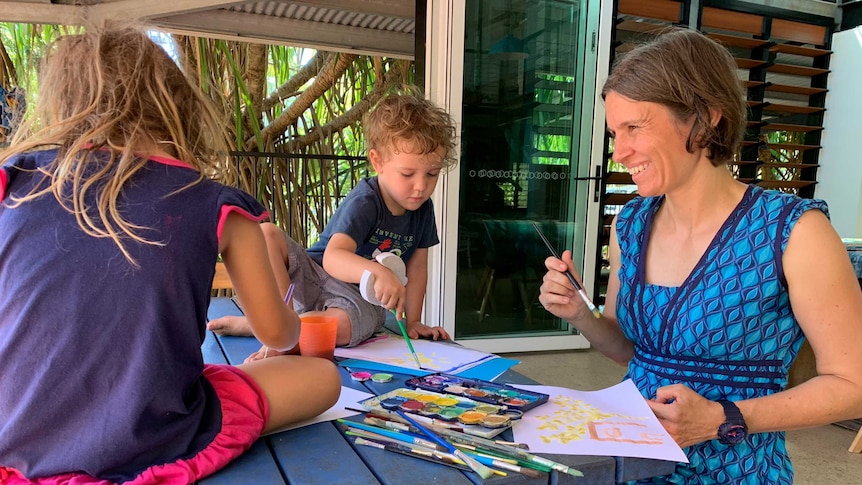 Dr Kerstin Zander sitting outside with her children who are painting