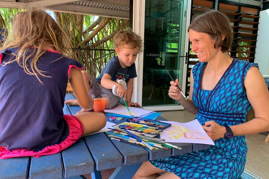Dr Kerstin Zander sitting outside with her children who are painting