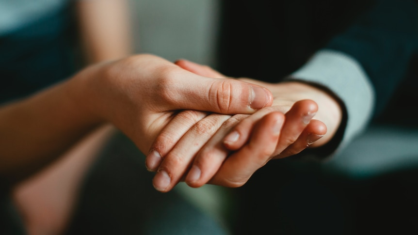 two pairs of hands clasping each other