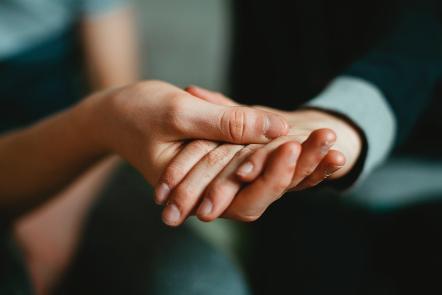 two pairs of hands clasping each other