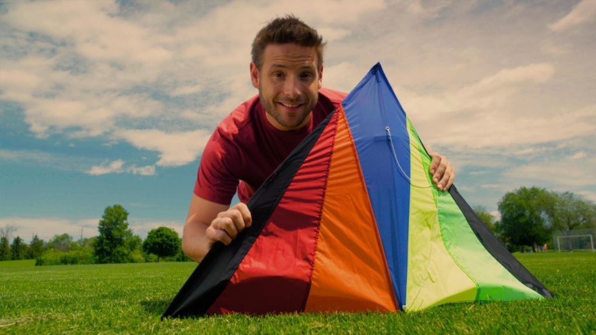 Man holds kite while sitting on grass