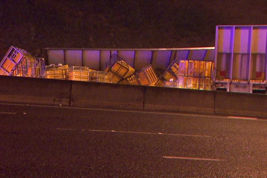 A semi-trailer with crates tumbling from it at night