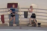 A man in a white singlet fights with another man in a blue shirt inside a jail.