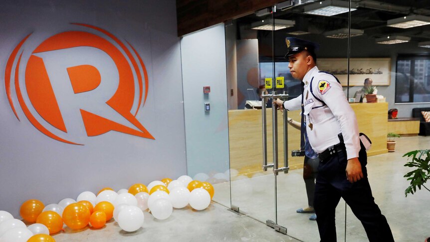 A guard opens a door at the office of Rappler.