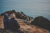 Two elderly people looking out to sea.