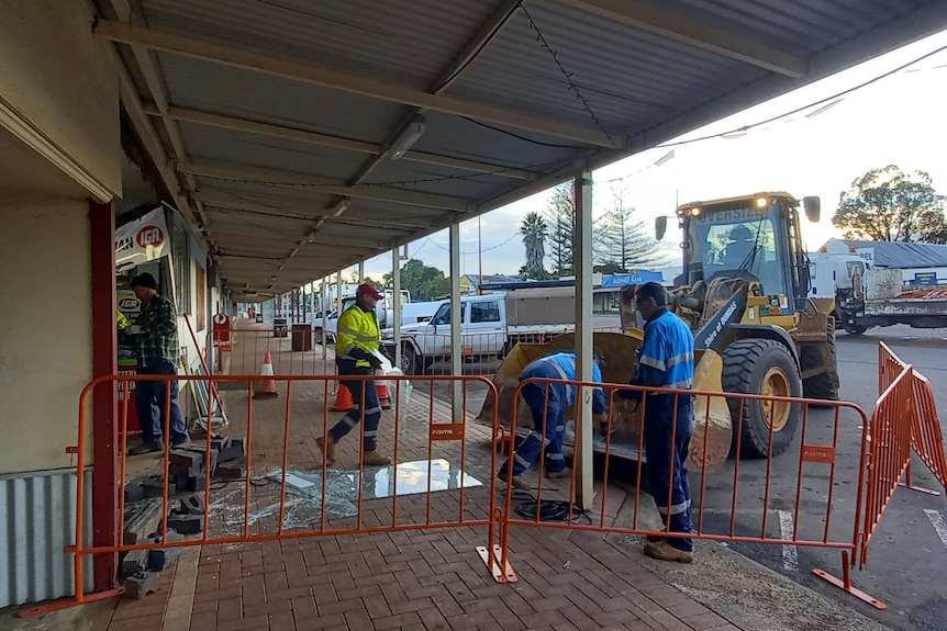 Council workers clean up the scene at a supermarket after a ram raid.   