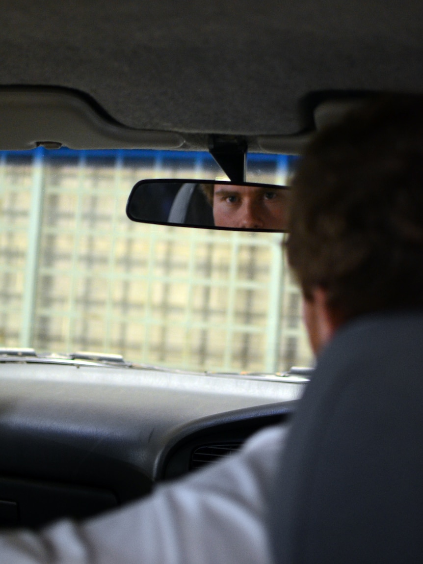 A man looks at the rear view-mirror of a car.