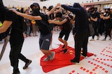Protesters step on a Chinese flag at a mall in Hong Kong. They have their hands on each others shoulders, and walk in a line.