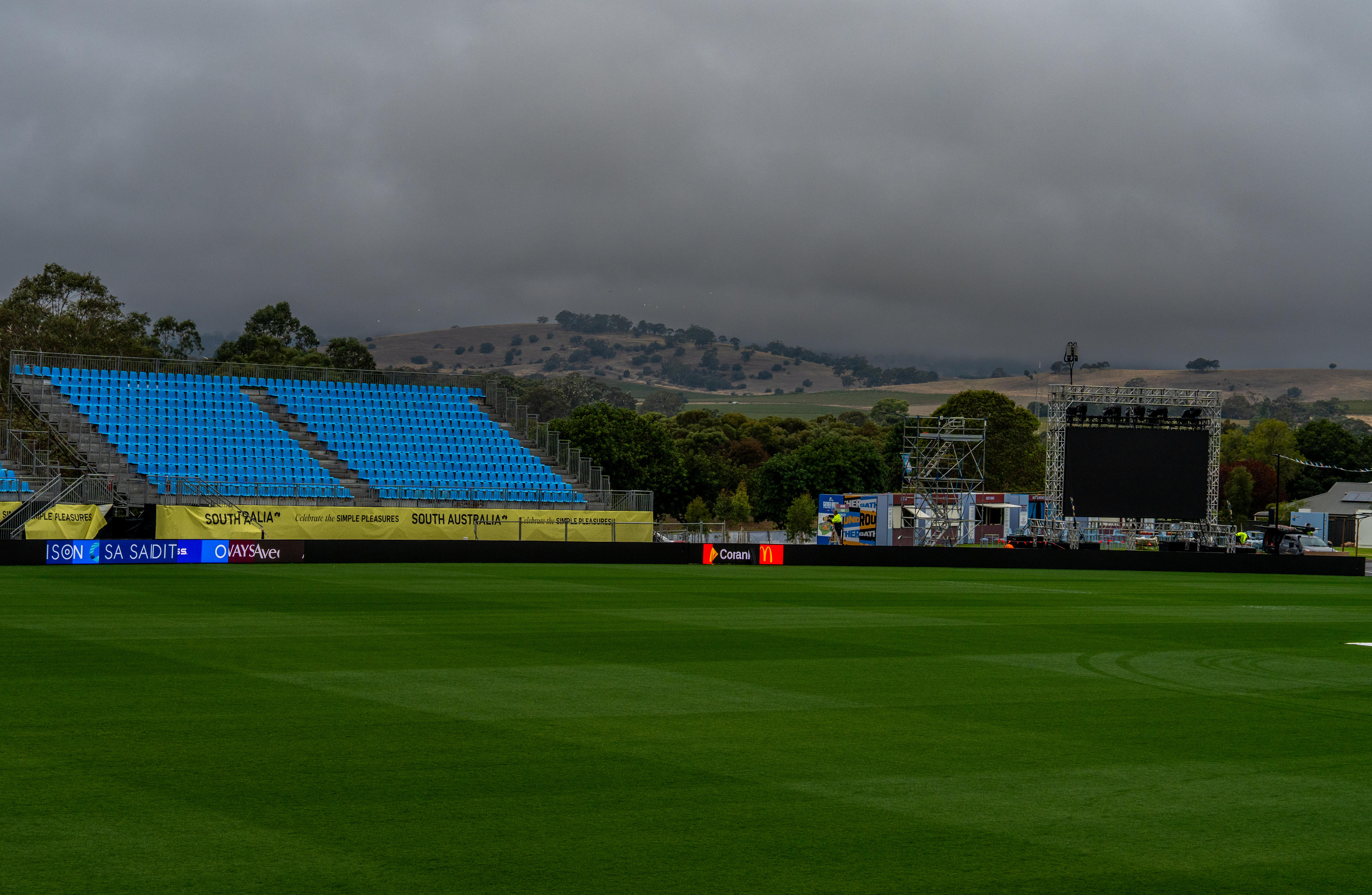 grey clouds above an empty footy stand and green oval