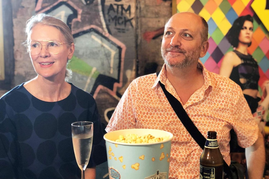 Carolle Walls and Leo Kaloglou sit at a table with popcorn and drinks at the Red Hill Cinemas Complex.