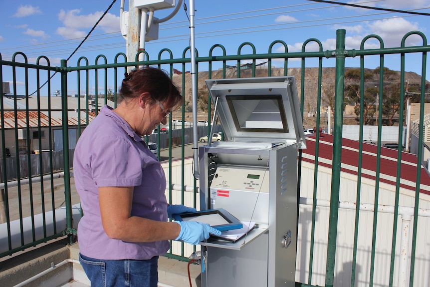 A woman wears blue gloves and touches a machine which acts like a filte