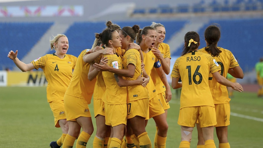 Matildas players embrace after scoring a goal