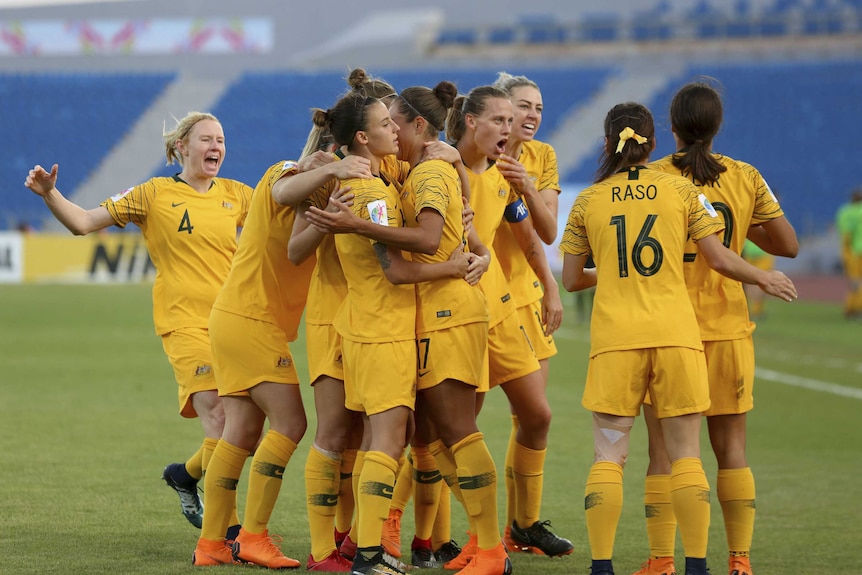 Matildas players embrace after scoring a goal