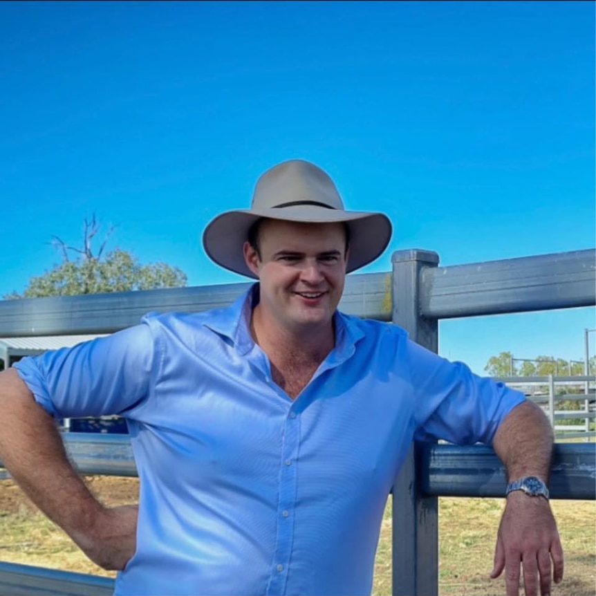 A man leans on a fence