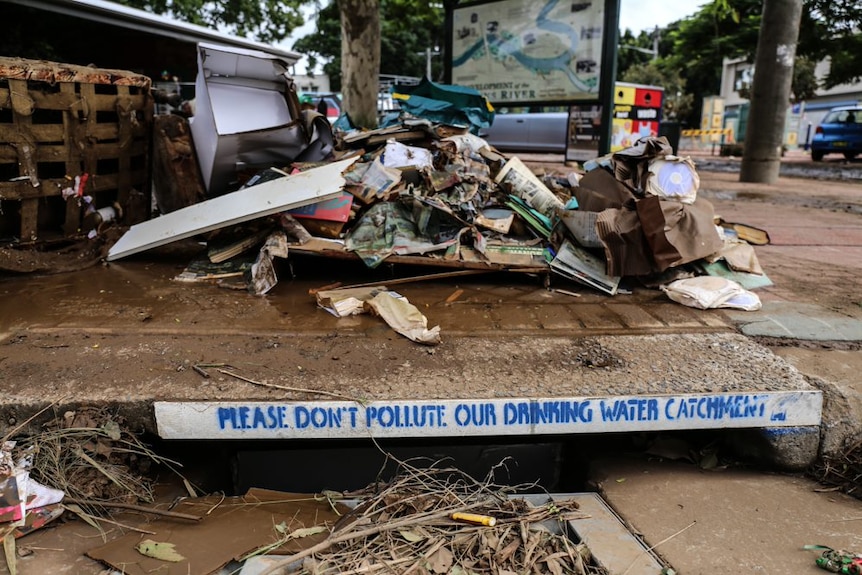 Rubbish and an old TV piled on a street after a flood.