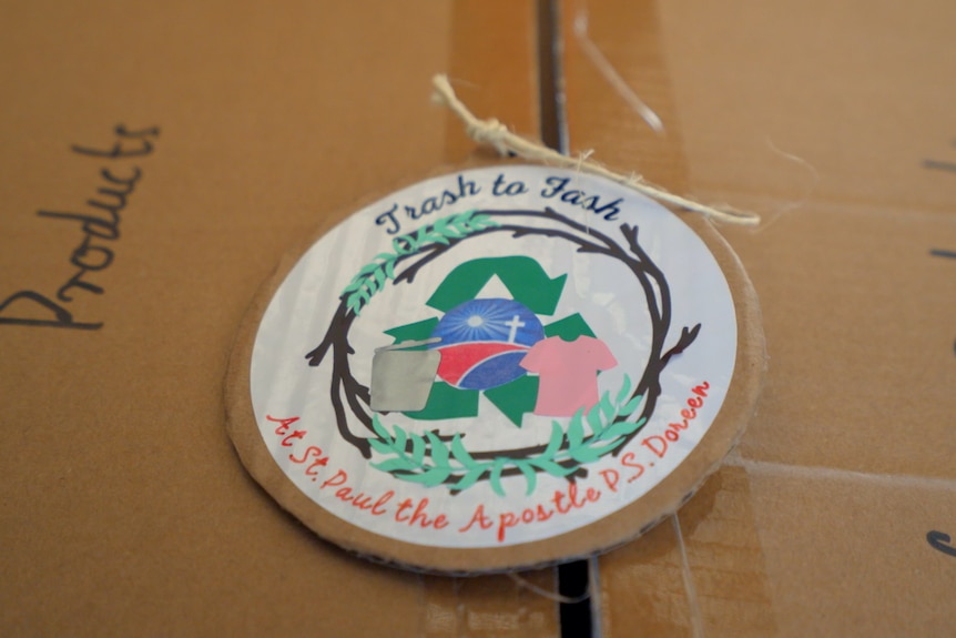 A cardboard label sits atop a box, saying 'Trash to Fash at St Paul the apostle P.S. Doreen'