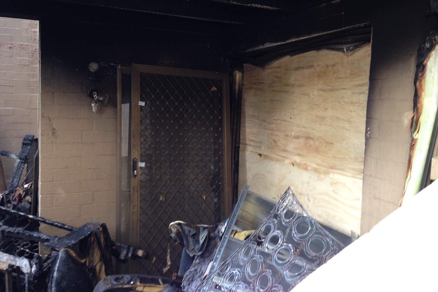 An apartment damaged by fire, with burnt objects across the floor.