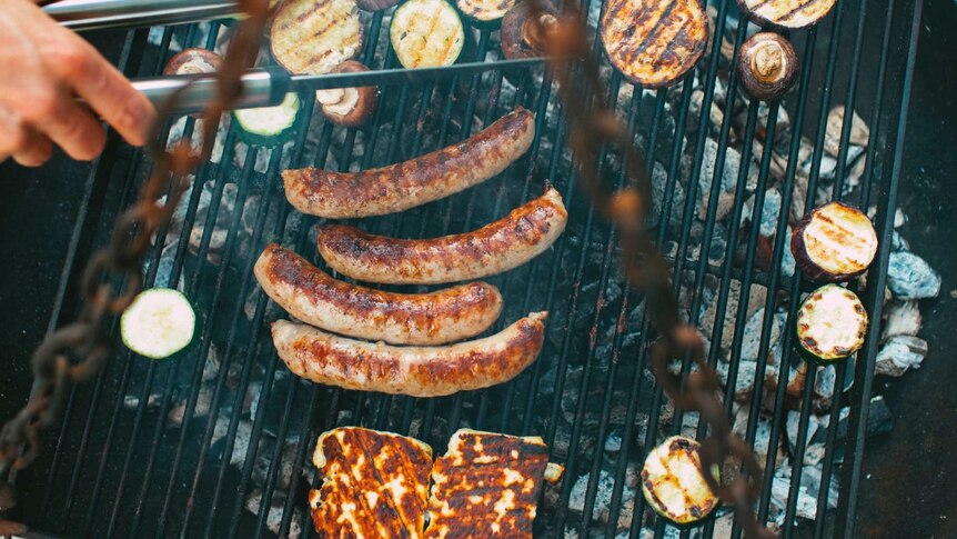 Sausages and veggies grilling over charcoal barbeque