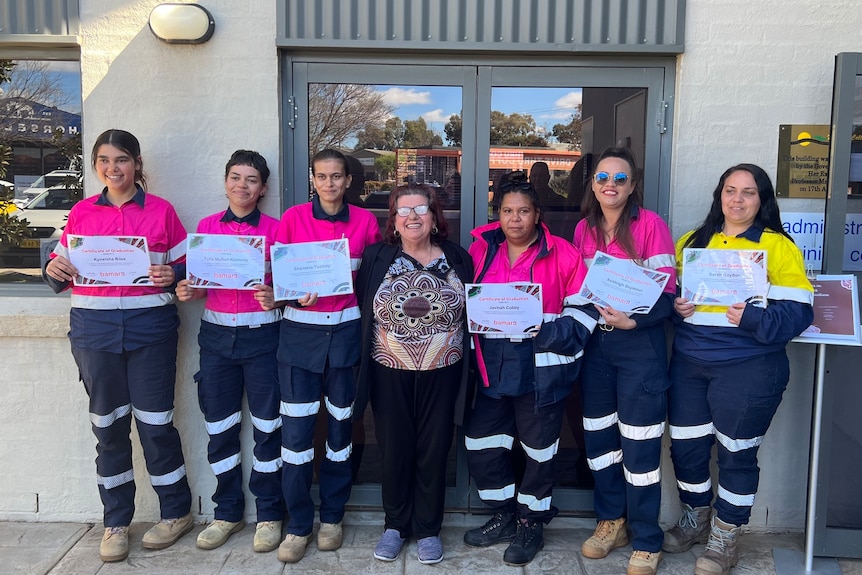 A group of women in high vis holding certificates.
