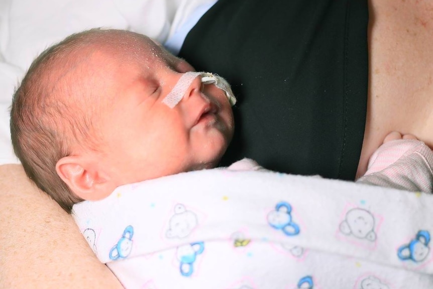 A premature baby with a tube in its nose get a cuddle from its mother.