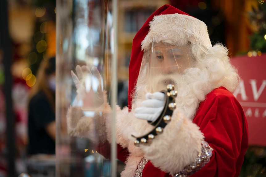 Beads of perspiration are seen on the face shield of a man dressed in a Santa Claus