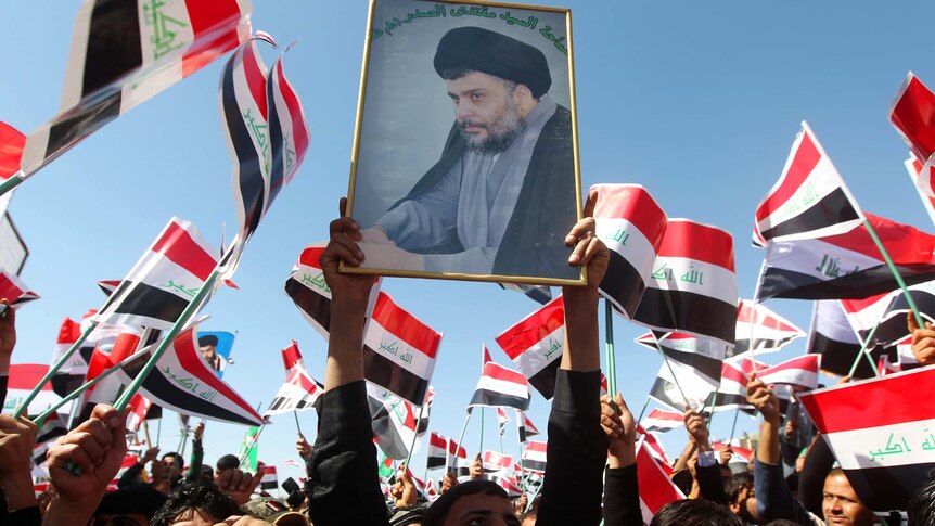 An Iraqi man holds up the portrait of anti-US cleric Moqtada al-Sadr