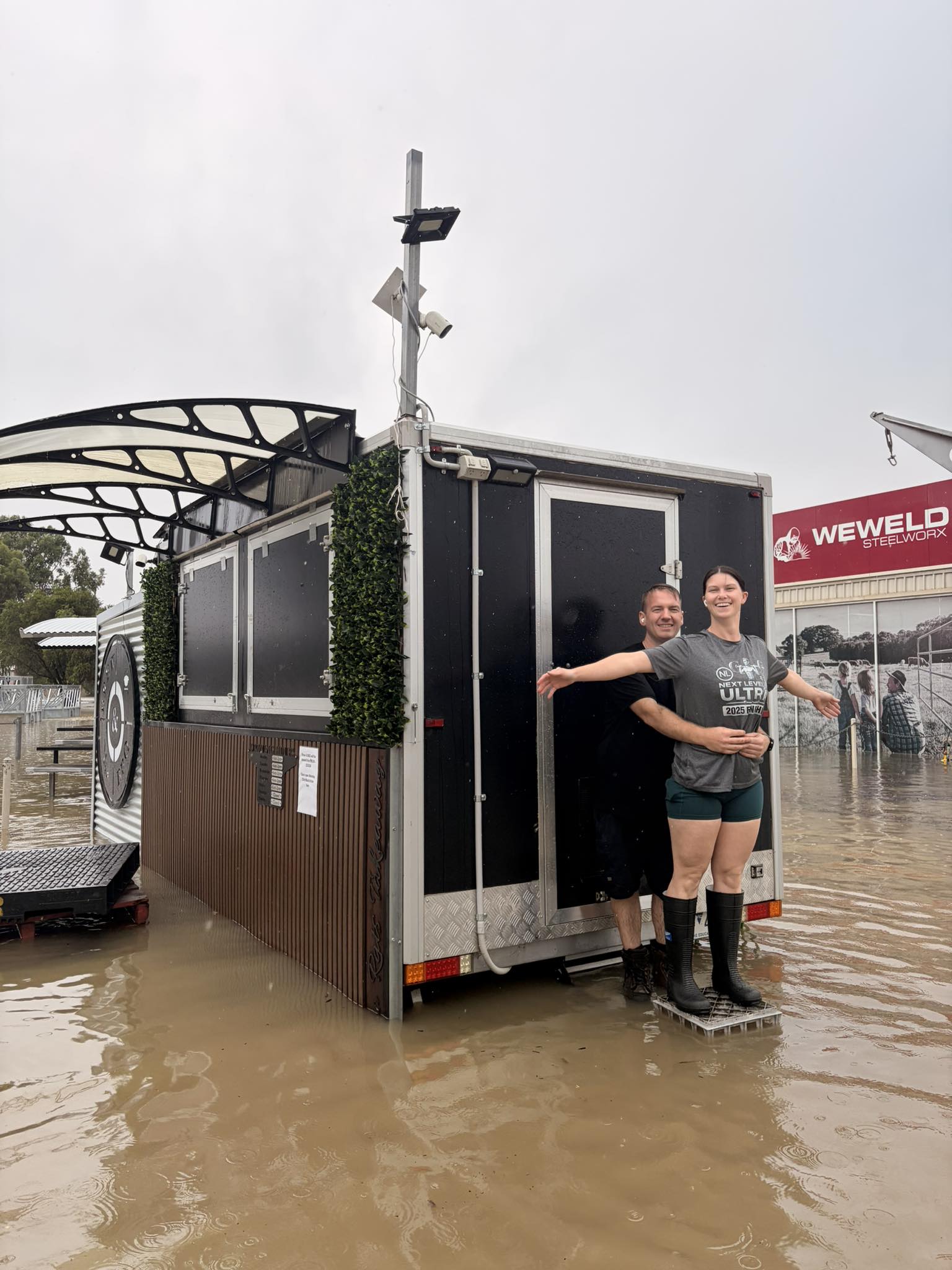 A flooded street with a coffee van and two people standing on the back reenacting the titanic movie
