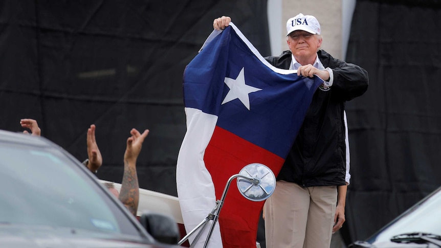 US President Donald Trump holds a flag of the state of Texas after receiving a briefing.