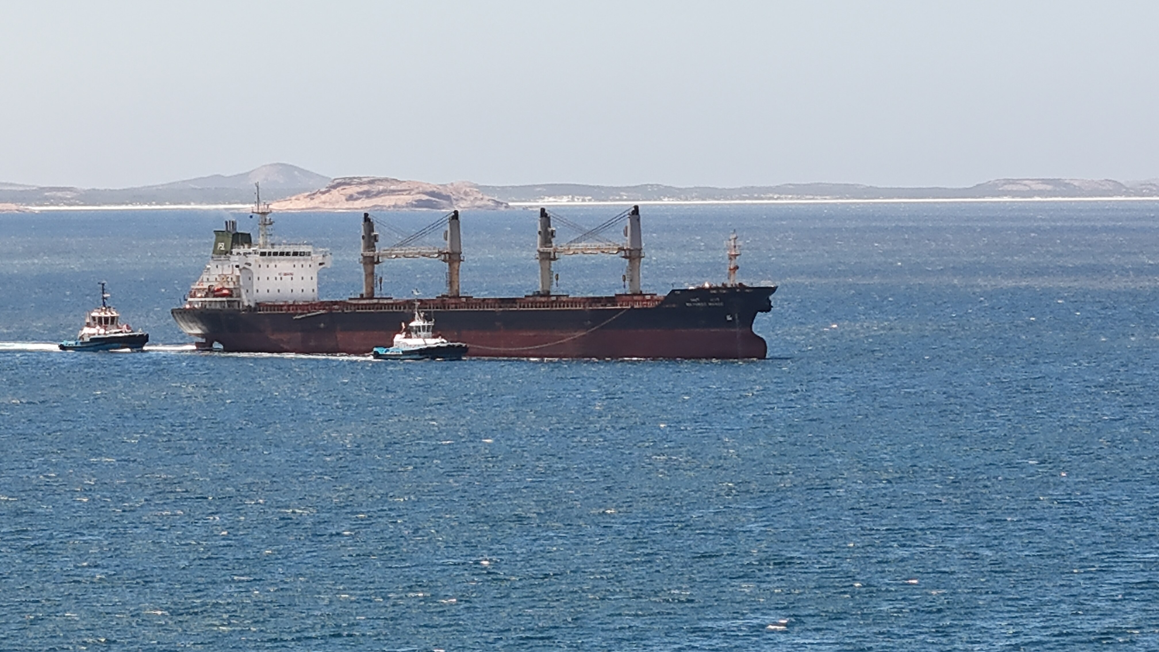 Tug boats escort a bulk carrier ship into Esperance Port.  