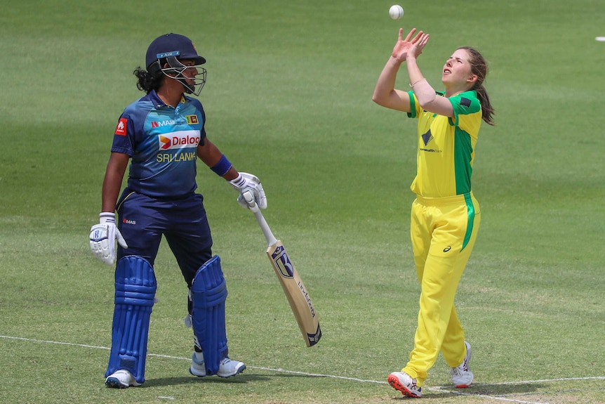 An Australian female cricketer stands to take a catch, as a Sri Lankan player looks on in a one-day international.