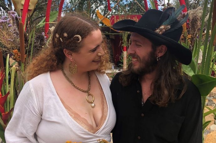 A woman and man look at each other beneath a red archway