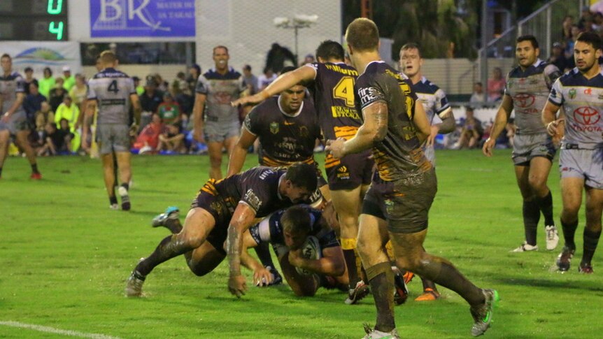 A Cowboys player is tackled in the trial game against the Broncos in Bundaberg