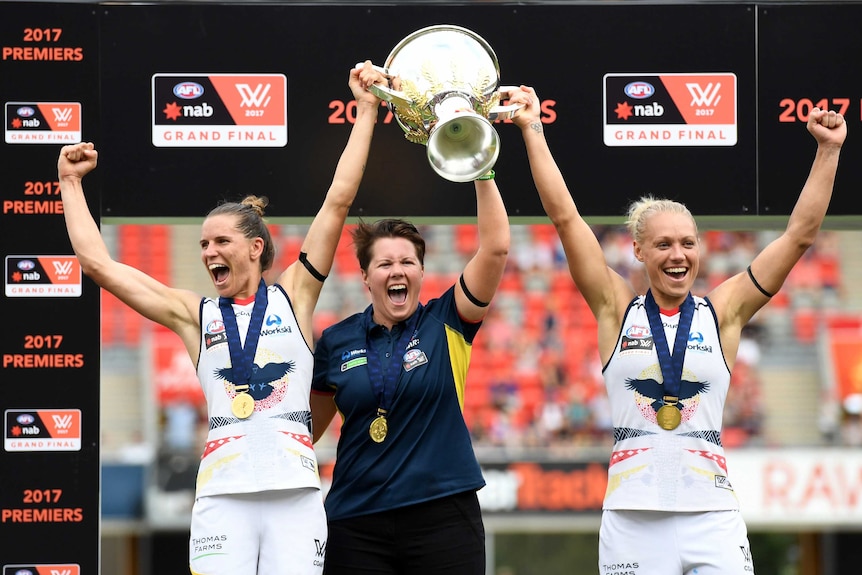 Adelaide Crows' Chelsea Randall (L) and Erin Phillips (R) and coach Bec Goddard with AFLW trophy.