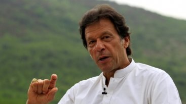 Imran Khan in a white shirt making a hand gesture and facing the camera