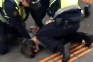 Two PSOs hold a youth on the ground during an arrest at the Bayswater train station,