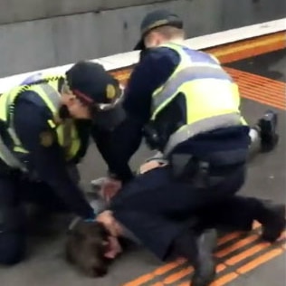 Two PSOs hold a youth on the ground during an arrest at the Bayswater train station,
