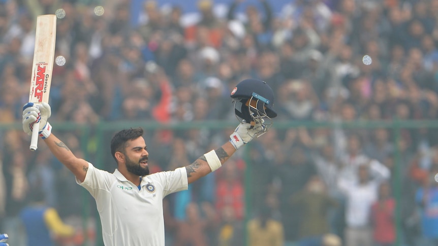 Virat Kohli raises his bat in smoggy conditions