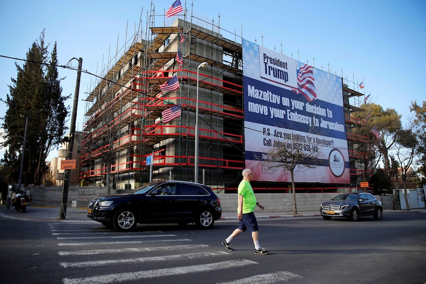 People walk past a giant banner on a building congratulating US President Donald Trump in Jerusalem.